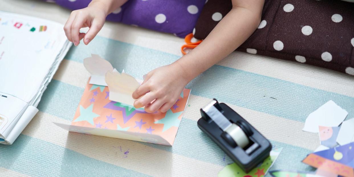 boy making a pop up card with coloured paper and sellotape