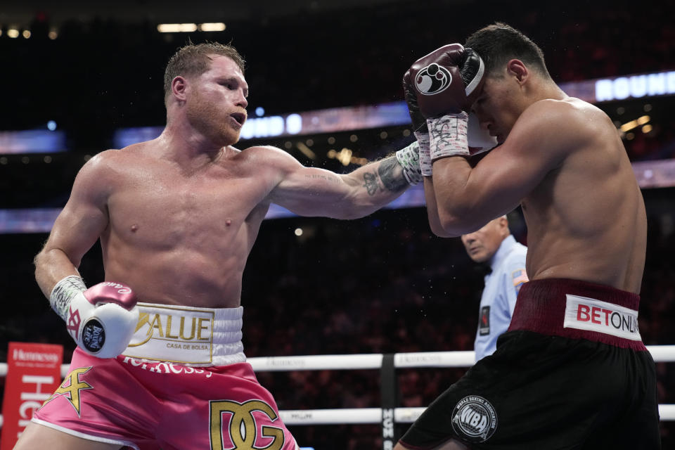 Canelo Alvarez, left, of Mexico, throws a punch against Dmitry Bivol, of Kyrgyzstan, during a light heavyweight title fight, Saturday, May 7, 2022, in Las Vegas. (AP Photo/John Locher)