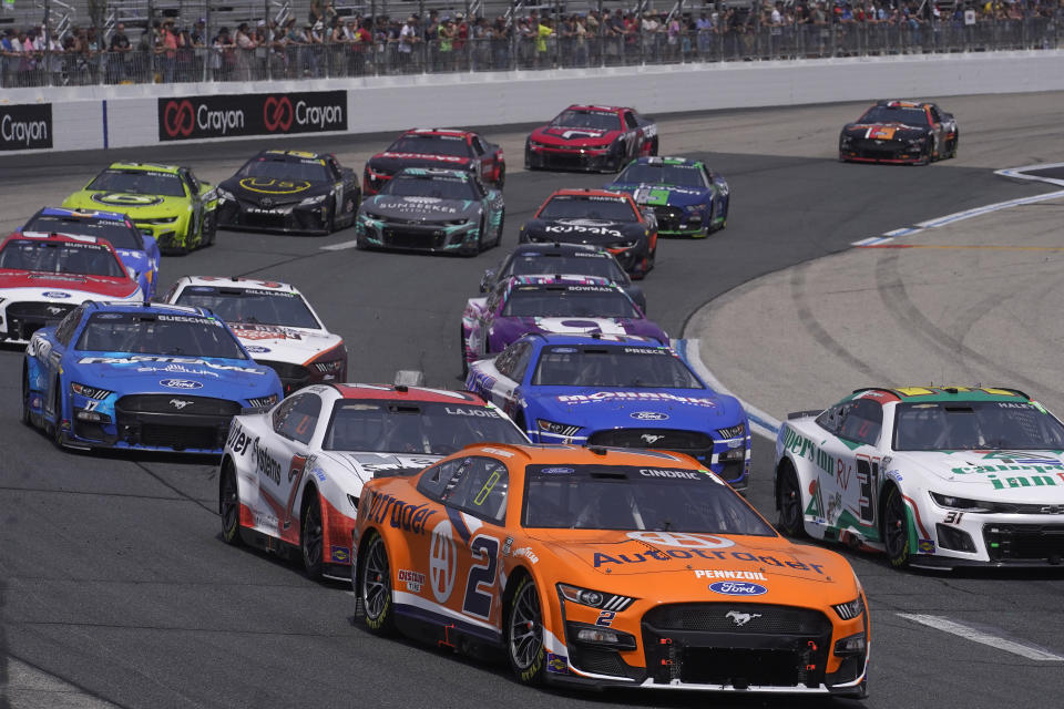 A tight pack of cars enters Turn 2 during the Crayon 301 NASCAR Cup Series race, Monday, July 17, 2023, at New Hampshire Motor Speedway, in Loudon, N.H. (AP Photo/Steven Senne)
