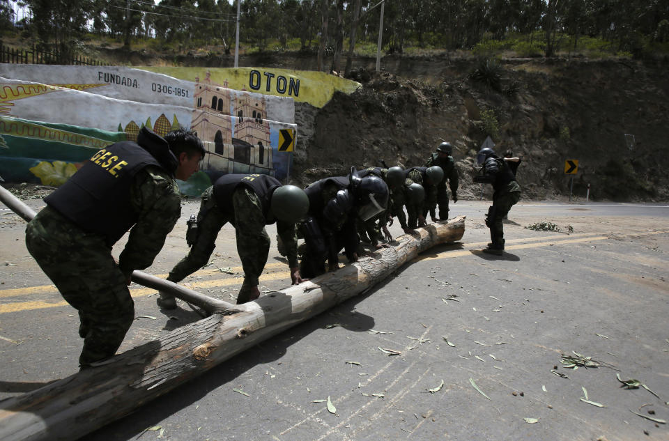 Soldiers remove a tree trunk used to block passage on a road in Oton, Ecuador, Friday, Oct. 4, 2019, during a nationwide transport strike that shut down taxi, bus and other services in response to a sudden rise in fuel prices. Ecuador's President Lenín Moreno, who earlier declared a state of emergency over the strike, vowed Friday that he wouldn't back down on the decision to end costly fuel subsidies, which doubled the price of diesel overnight and sharply raised gasoline prices. (AP Photo/Dolores Ochoa)