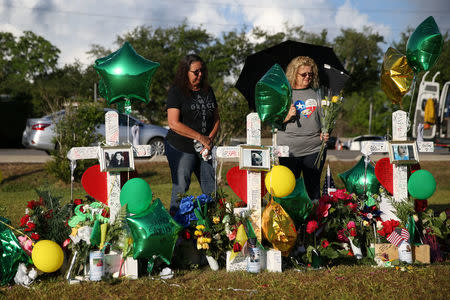 Andrea Clements (L) and Cindy Cappadona pay their respects at a makeshift memorial left in memory of the victims killed in a shooting at Santa Fe High School in Santa Fe, Texas, U.S., May 23, 2018. REUTERS/Loren Elliott