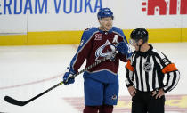 Colorado Avalanche center Nathan MacKinnon, left, back in the lineup after missing three games, jokes with referee Gord Dwyer in the second period of an NHL hockey game against the Arizona Coyotes Wednesday, March 10, 2021, in Denver. (AP Photo/David Zalubowski)