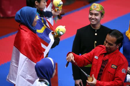 Taekwondo – 2018 Asian Games – Women’s Individual Poomsae, Final - JCC Plenary Hall, Jakarta, Indonesia – August 19, 2018 – Defia Rosmaniar of Indonesia receives her gold medal from Indonesian President Joko Widodo. REUTERS/Cathal Mcnaughton