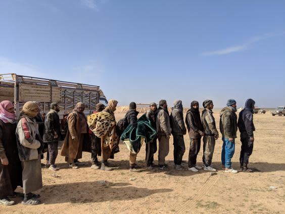 Men who fled the last Isis-held area of Syria line up to be questioned by American and Kurdish intelligence officials (Richard Hall)