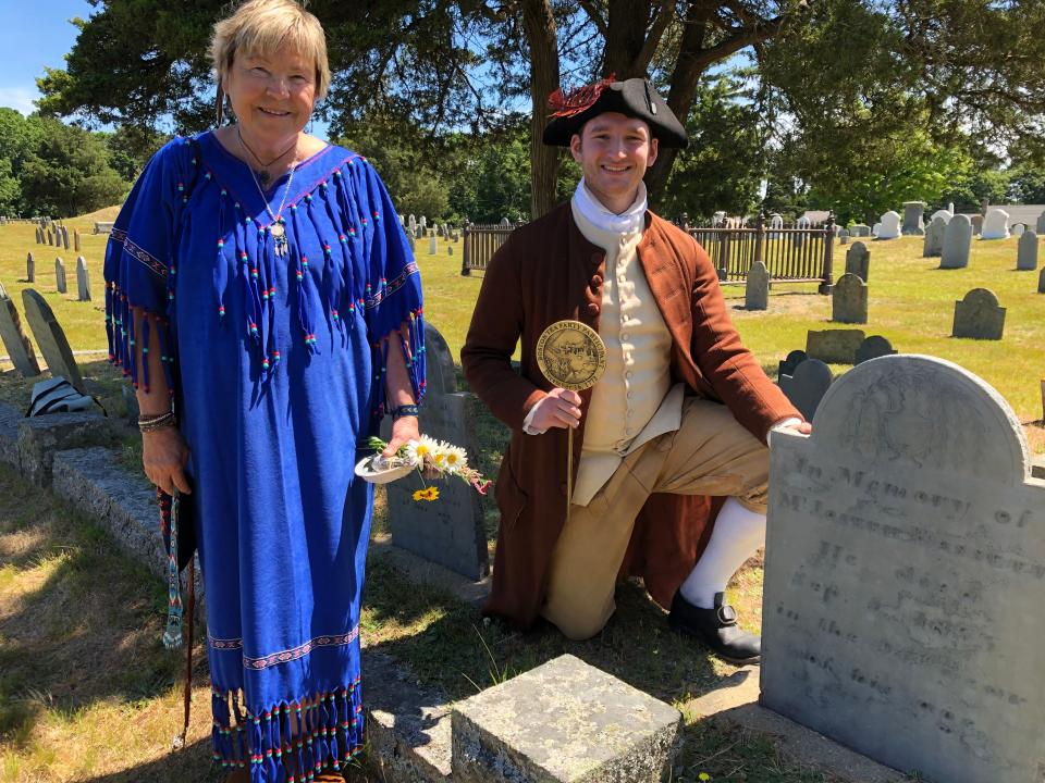 Deb Bianci, left, a volunteer with the Friends of Ancient Cemetery, and Ryan Stack, portraying Capt. Joseph Bassett pose Wednesday with the Tea Party commemorative medal at the grave of Captain Bassett after a short ceremony in Yarmouth Port. Denise Coffey /Cape Cod Times