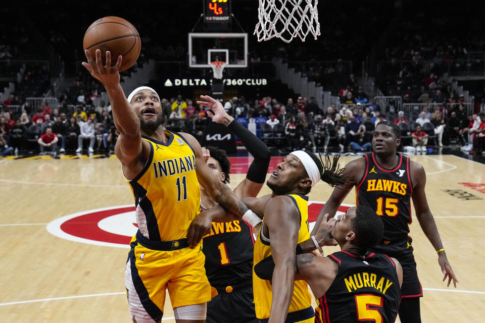 Indiana Pacers forward Bruce Brown (11) goes in for a shot as Atlanta Hawks guard Dejounte Murray (5) defends and Pacers center Myles Turner watches during the first half of an NBA basketball game Friday, Jan. 12, 2024, in Atlanta. (AP Photo/John Bazemore)