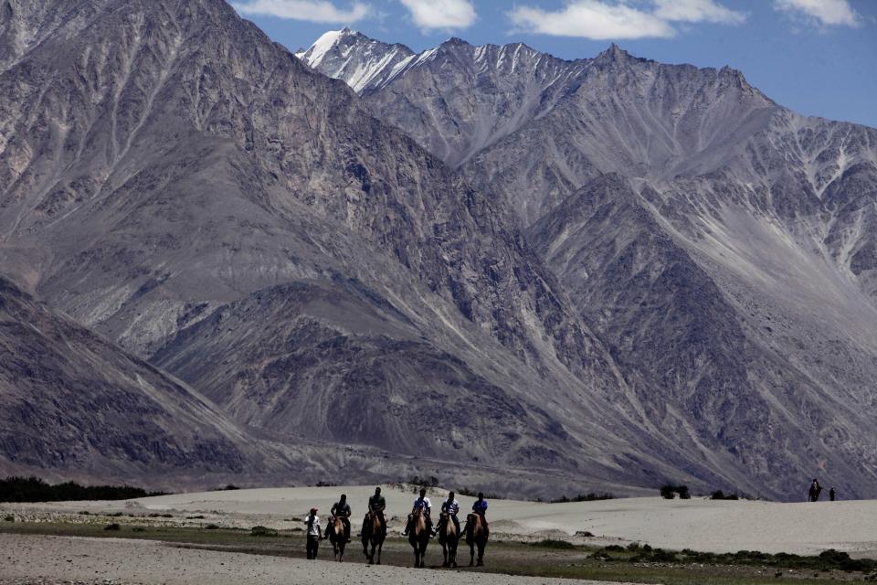 FILE- In this July 20, 2011 file photo, tourists ride double hump camels at Nubra valley, in Ladakh, India. Tensions along the disputed India-China border seem to be getting worse rather than better, three months after their deadliest confrontation in decades in June. The Asian giants accused each other this week of sending soldiers into each other’s territory and fired warning shots for the first time in 45 years, raising the specter of full-scale military conflict. (AP Photo/Channi Anand, File)