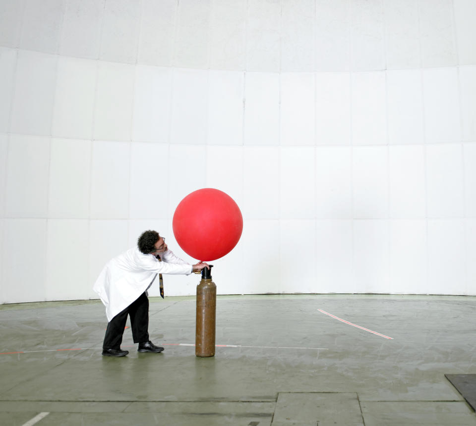 Man inflating balloon with helium.