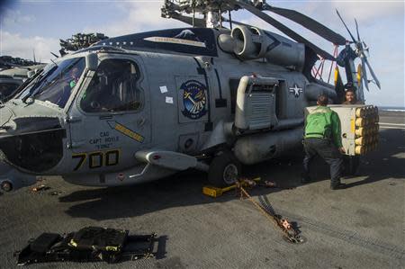 Sailors assigned to the Saberhawks of Helicopter Maritime Strike Squadron Seven Seven (HSM-77) remove equipments from a MH-60R Seahawk helicopter on board aircraft carrier USS George Washington to make room for the transportation of cargo and personnel, as they travel via the "strike group" route to the Philippines to support humanitarian efforts in response to Typhoon Haiyan, in this photo taken November 13, 2013. REUTERS/Mass Communication Specialist 3rd Class Paolo Bayas/U.S. Navy/Handout via Reuters