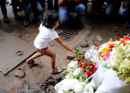 A child place flowers at a makeshift memorial near the site, to pay tribute to the victims of the attack on the Holey Artisan Bakery and the O'Kitchen Restaurant, in Dhaka, Bangladesh, July 3, 2016. REUTERS/Mohammad Ponir Hossain