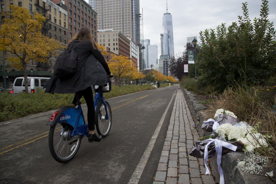 FILE - A bicyclist passes bouquets of flowers left by Argentine President Mauricio Macri and New York Mayor Bill de Blasio at the site of the terrorist attack on bicyclists, Nov. 6, 2017, in New York. Relatives of eight people killed in the Halloween terror attack on a New York City bike path, as well as those who were injured, are expected to speak at a Wednesday, May 17, 2023, sentencing hearing for an Islamic extremist who prosecutors say deserves multiple life sentences. (AP Photo/Mark Lennihan, File)