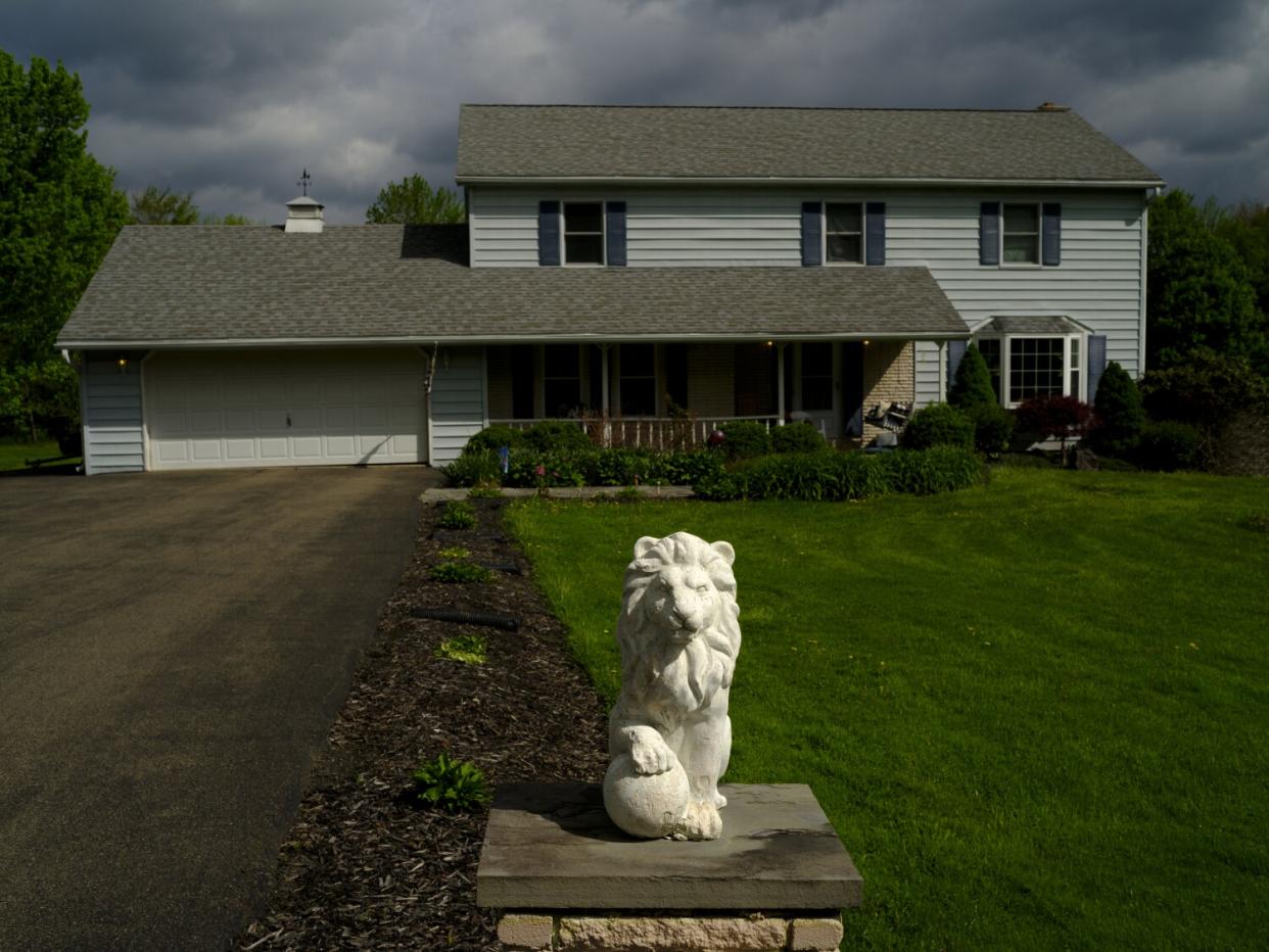 A two-story home sits behind a big lawn.