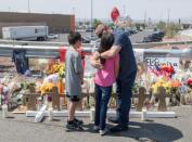 Members of the Soto family embrace beside a makeshift memorial after the shooting that left 22 people dead at the Cielo Vista Mall WalMart in El Paso, Texas, on August 5, 2019