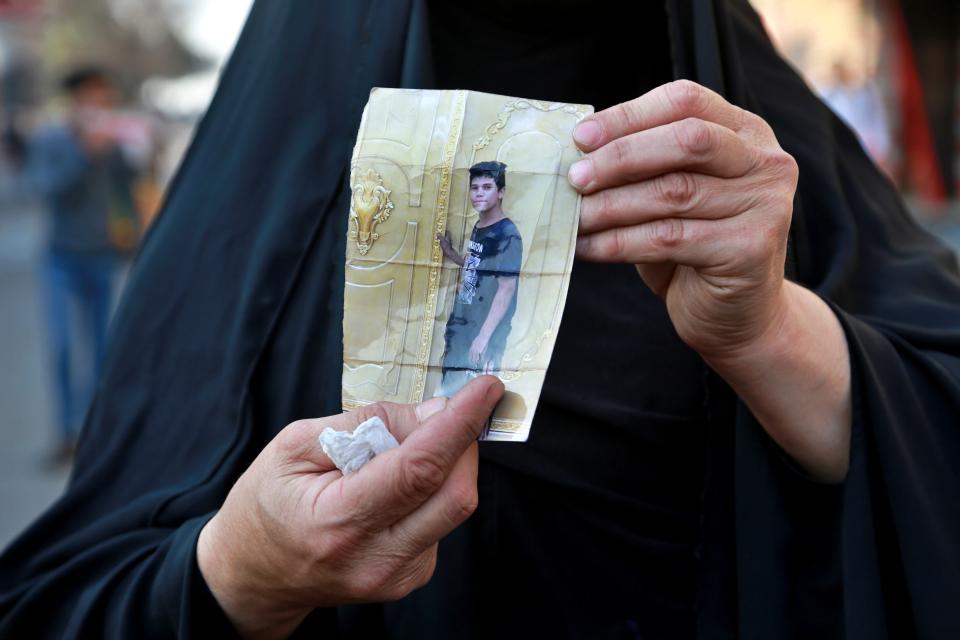 A mother looking for her protester son, in the picture, who has been missing for 6 days, while protesters gather Rasheed Street during clashes in Baghdad, Iraq, Wednesday, Nov. 27, 2019. (AP Photo/Khalid Mohammed)