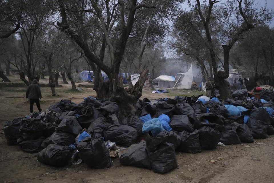 A migrant walks in front garbage dumped outside the Moria refugee camp on the northeastern Aegean island of Lesbos, Greece, on Tuesday, Jan. 21, 2020. Some businesses and public services on the eastern Aegean island are holding a 24-hour strike on Wednesday to protest the migration situation, with thousands of migrants and refugees are stranded in overcrowded camps in increasingly precarious conditions. (AP Photo/Aggelos Barai)