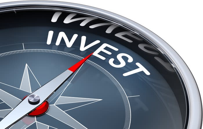 A compass pointing towards the word invest