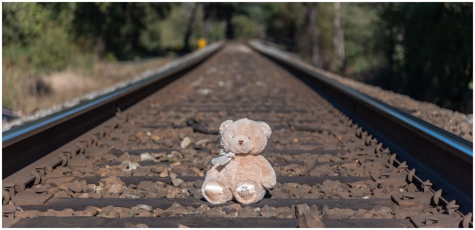 Teddy bear sitting on railway tracks