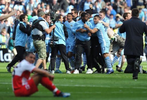 Manchester City's players and supporters celebrate on the pitch after their 3-2 victory over Queens Park Rangers. Sergio Aguero's last minute goal sealed the most enthralling title duel in years