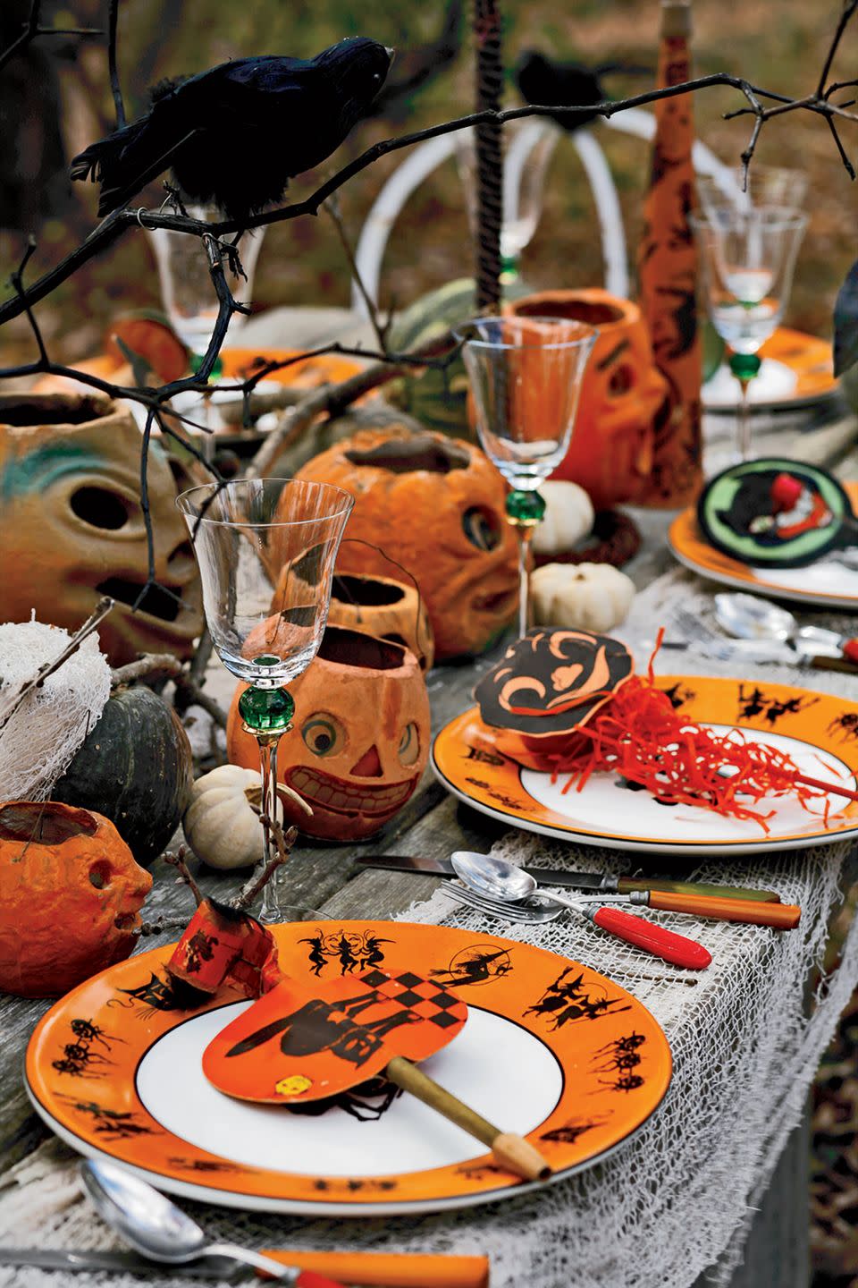 <p>A faux feathered bird, like a black crow, is the perfect addition to a Halloween table. Set a few on top of black spray-painted tree branches to achieve a realistic feel. Don't forget to complete the look with everything from creepy pumpkin designs to a white gauze tablecloth.</p>