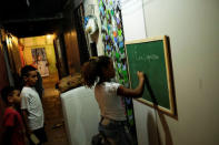 Children write on a chalkboard in a hallway of the abandoned Prestes Maia textile factory occupied by a homeless movement in downtown Sao Paulo, Brazil May 12, 2018. REUTERS/Nacho Doce