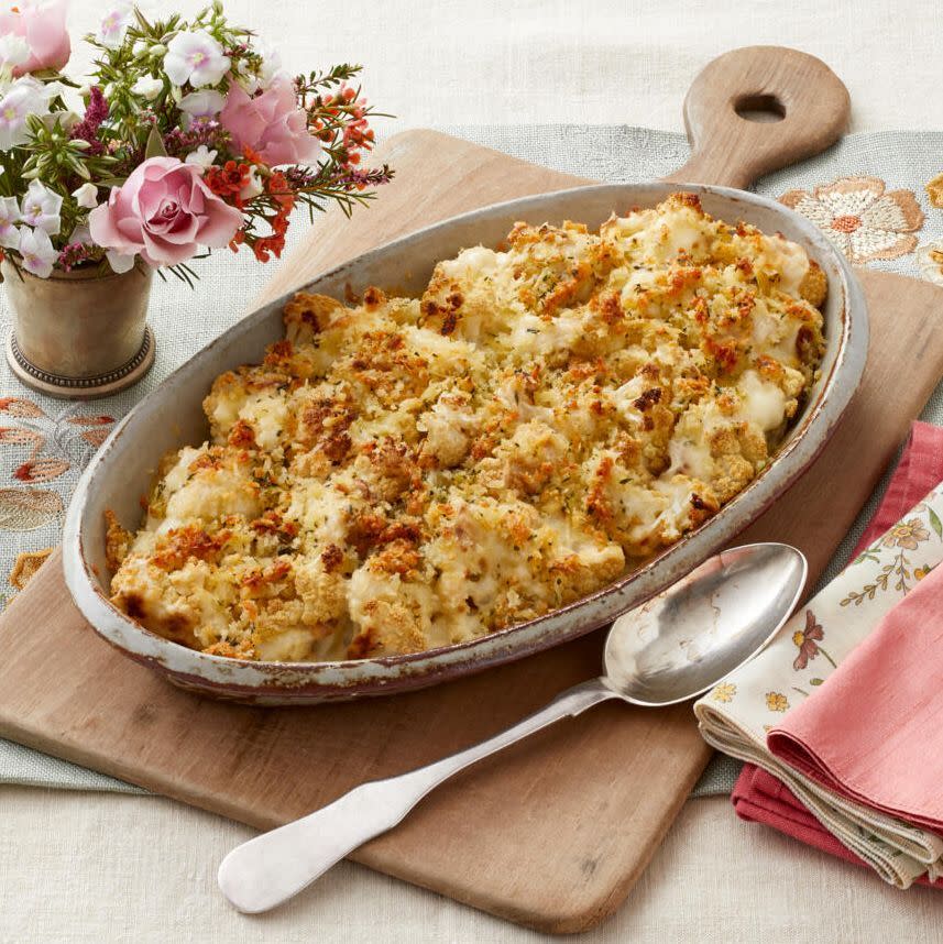 easter side dishes cauliflower gratin on wood board with flowers in back