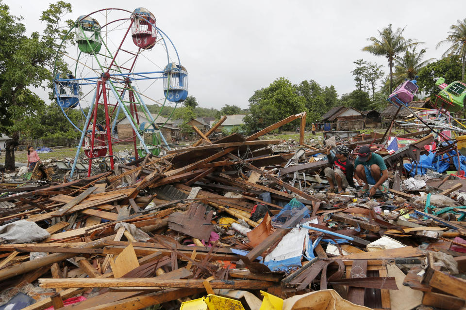 People collect usable items in debris, following Saturday's tsunami in Sumur, Indonesia, Tuesday, Dec. 25, 2018. The Christmas holiday was somber with prayers for tsunami victims in the Indonesian region hit by waves that struck without warning Saturday night.(AP Photo/Tatan Syuflana)