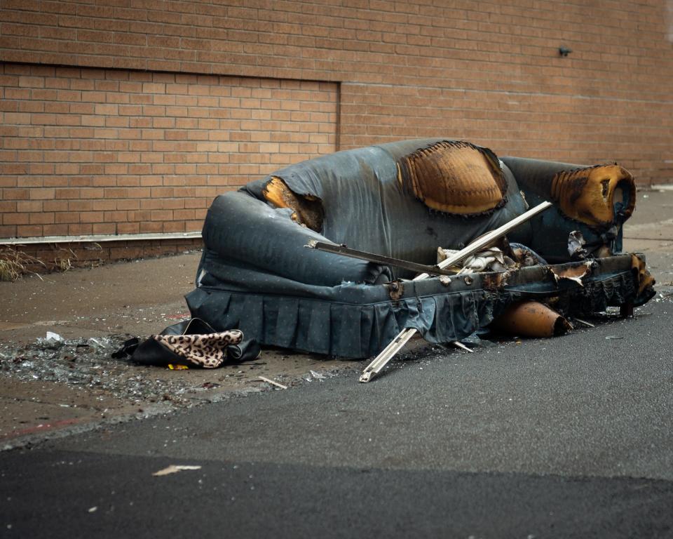 A burned couch sits on the sidewalk next to the Lillian Cooper Apartments at 276 Genesee Street in Utica on Wednesday, November 30, 2022.