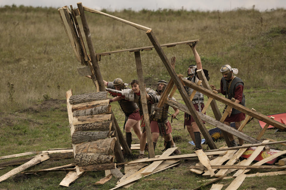 Men wearing Roman soldiers outfits destroy a wooden structure during the Romula Fest historic reenactment event in the village of Resca, Romania, Sunday, Sept. 4, 2022. (AP Photo/Andreea Alexandru)