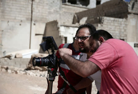 Syrian director Humam Husari (R) and cameraman Sami al-Shami (C) operate a camera as they film a scene in the rebel-held besieged town of Zamalka, in the Damascus suburbs, Syria September 19, 2016. REUTERS/Bassam Khabieh