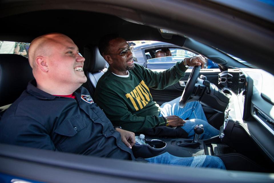 Ann Arbor Huron High School principal Ché Carter, center, shares a laugh with automotive technology instructor Vince Snyder inside of a 2024 Ford Mustang that is donated to their school through a partnership between Gene Butman Ford and Ford Motor Company at the dealership in Ypsilanti on Friday, May 31, 2024