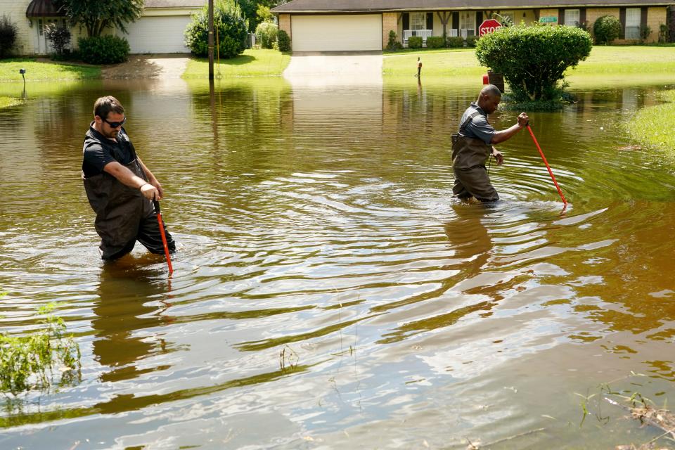 Hinds County Emergency Management Operations deputy director Tracy Funches, right, and operations coordinator Luke Chennault, wade through flood waters in northeast Jackson, Miss., Monday, Aug. 29, 2022, as they check water levels. Flooding affected a number of neighborhoods that are near the Pearl River