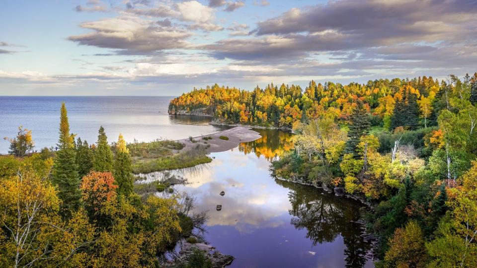 beautiful reflections of clouds and autumn colors on the baptism river where it meets lake superior at tettegouche state park, minnesota