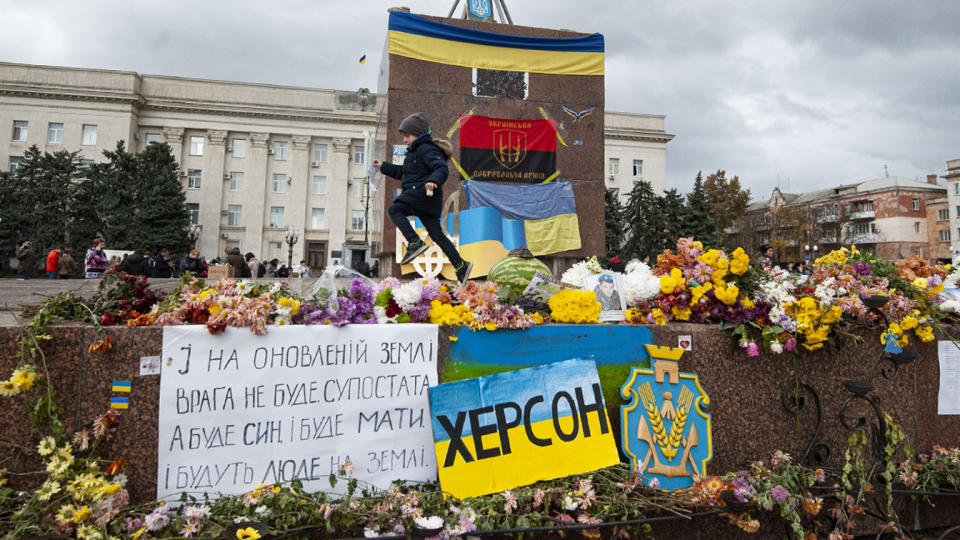 Flags, signs and floral tributes left in front of the Kherson Regional State Administration.