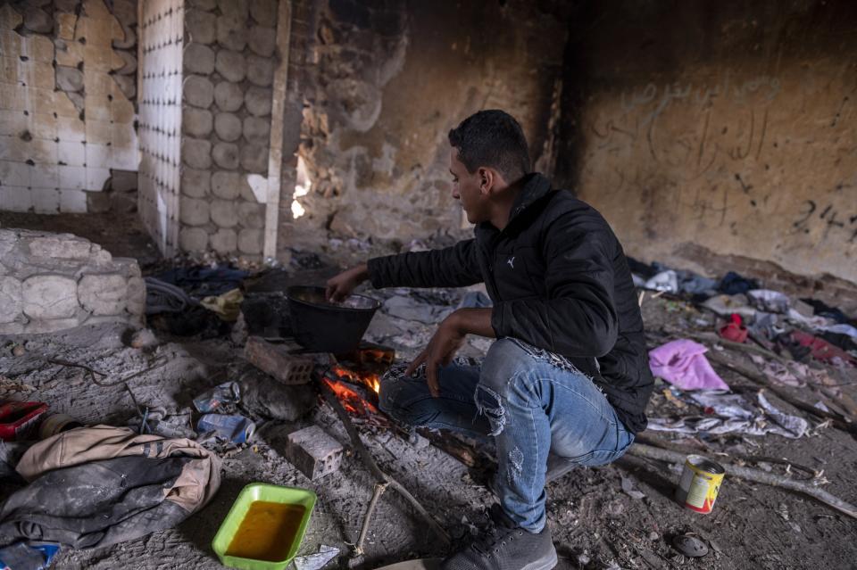 A Syrian man cooks inside an abandoned army outpost near Ieropigi village, northern Greece, at the Greek - Albanian border, on Tuesday, Sept. 28, 2021. A relatively smooth section of Greece's rugged border with Albania is turning into a major thoroughfare north for migrants in Greece seeking a better life in Europe's prosperous heartland. (AP Photo/Giannis Papanikos)