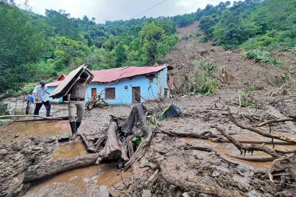 A security personnel carries the belongings of a villager from the site of a landslide after heavy rains at Jadon village in Solan district of India’s Himachal Pradesh (AFP via Getty Images)