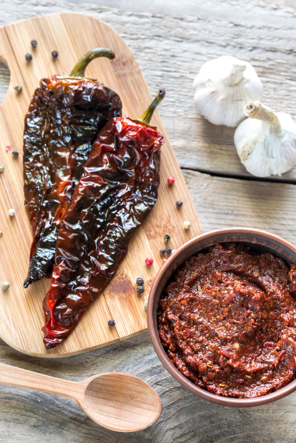 Chipotle peppers on a cutting board and a bowl of adobo sauce.