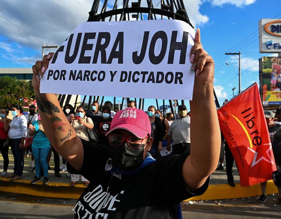 A woman holds a placard reading “JOH (Honduran President Juan Orlando Hernandez) Out” at a rally in Tegucigalpa on 30 March.