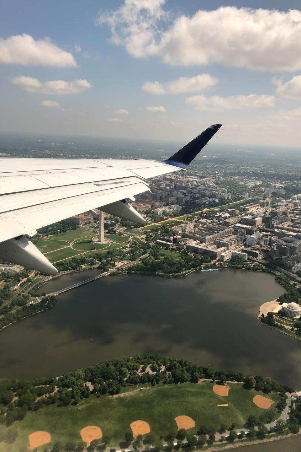 The view of a city and golf course from an airplane passenger window