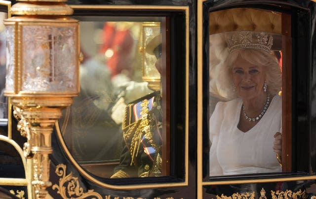 The Queen smiles in the carriage as she leaves the Palace in procession to the House of Lords 