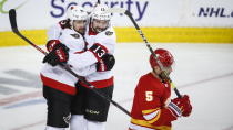 Ottawa Senators' Colin White, left, celebrates his goal with teammate Nicholas Paul as Calgary Flames' Mark Giordano skates away during the second period of an NHL hockey game, in Calgary, Alberta, Sunday, March 7, 2021. (Jeff McIntosh/The Canadian Press via AP)