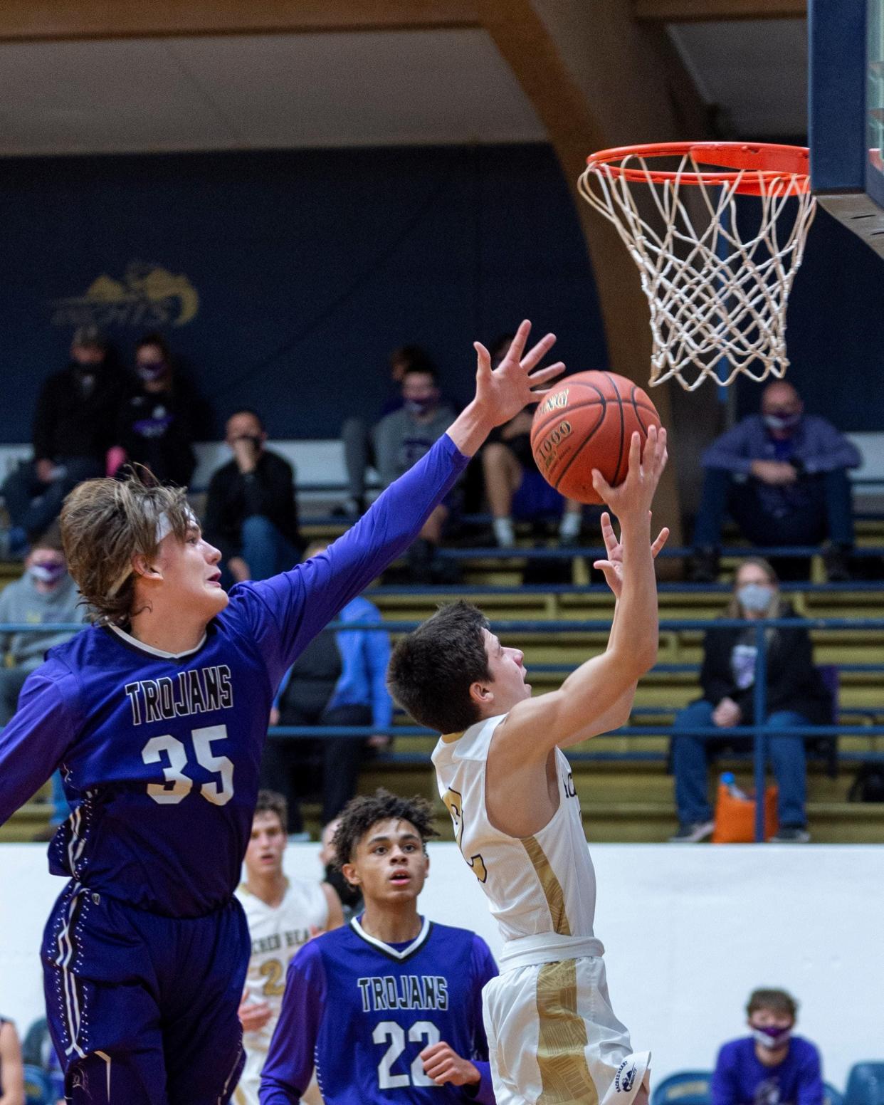 Southeast of Saline's Eli Sawyers (35) attempts to block a shot against Sacred Heart's Michael Matteucci (2) during their game in December 2020 at the Sacred Heart gym.