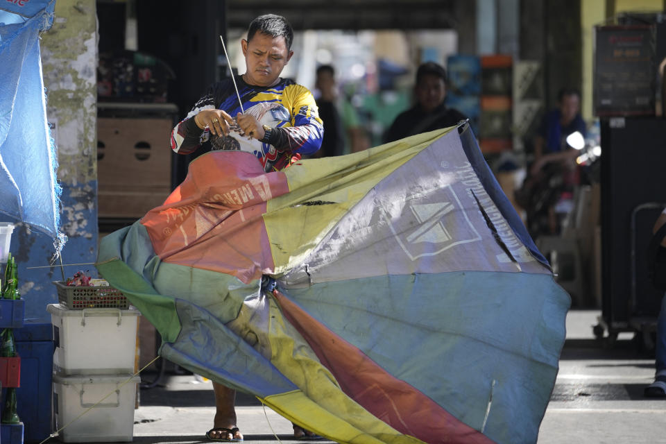 A vendor fixes his old umbrella as he prepares for another hot day in Manila, Philippines on Monday, April 29, 2024. Millions of students in all public schools across the Philippines were ordered to stay home Monday after authorities cancelled in-person classes for two days as an emergency step due to the scorching heat and a public transport strike. (AP Photo/Aaron Favila)
