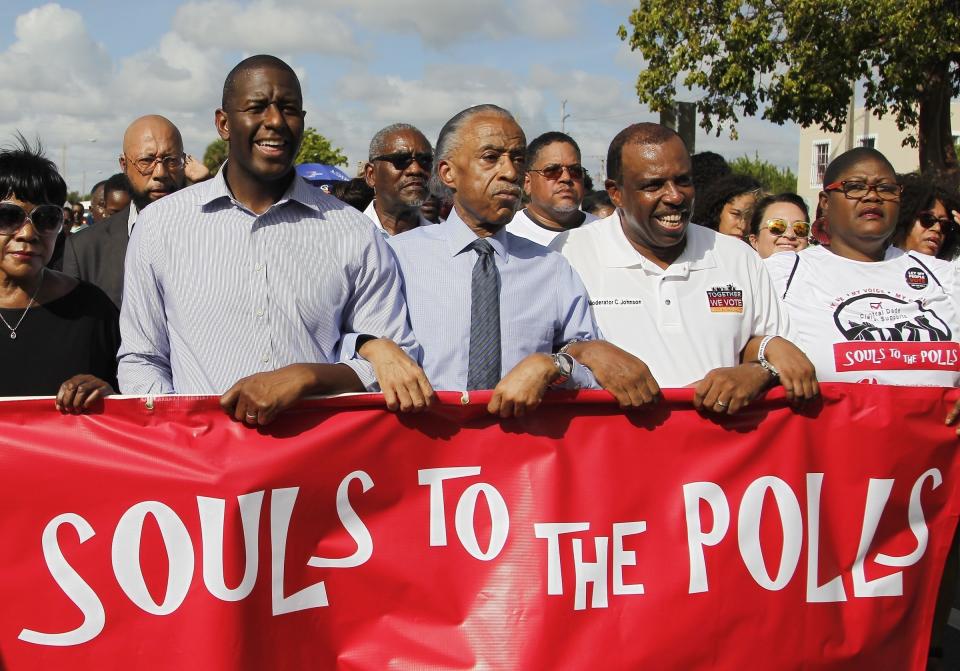FILE- In this Nov. 4, 2018 file photo Florida Democratic gubernatorial candidate Andrew Gillum, center, marches with Al Sharpton, and local politicians and supporters, as part of the "Souls to the Polls" in Miami. Florida voters on Tuesday, Nov. 6 will elect a U.S. senator, a new governor, three Cabinet members and several new members of Congress while deciding to support or approve 12 proposed changes to the state's constitution. (Carl Juste/Miami Herald via AP, File)