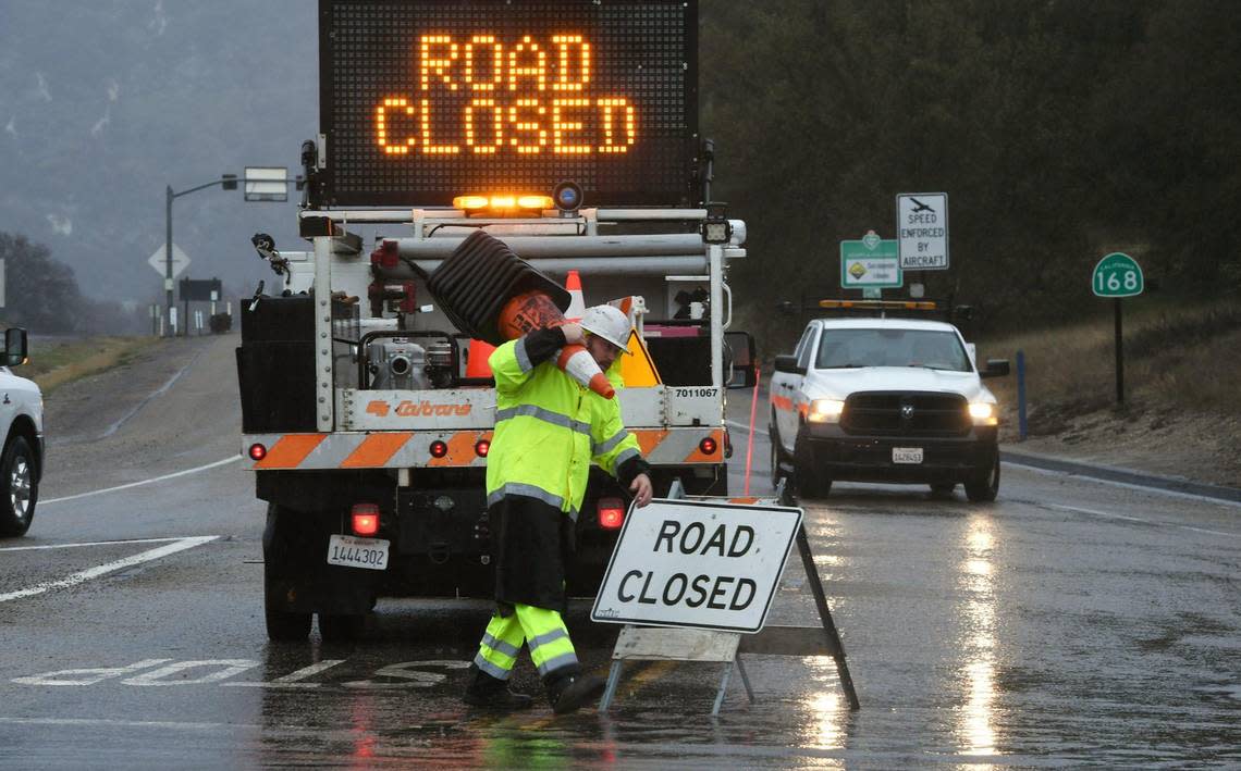 A Caltrans worker helps place traffic cones at the base of the 168 four-lane, the intersection of HWY 168 and Lodge Road after mudslides and rockfall created hazards Monday, Jan. 9, 2023 in Fresno.