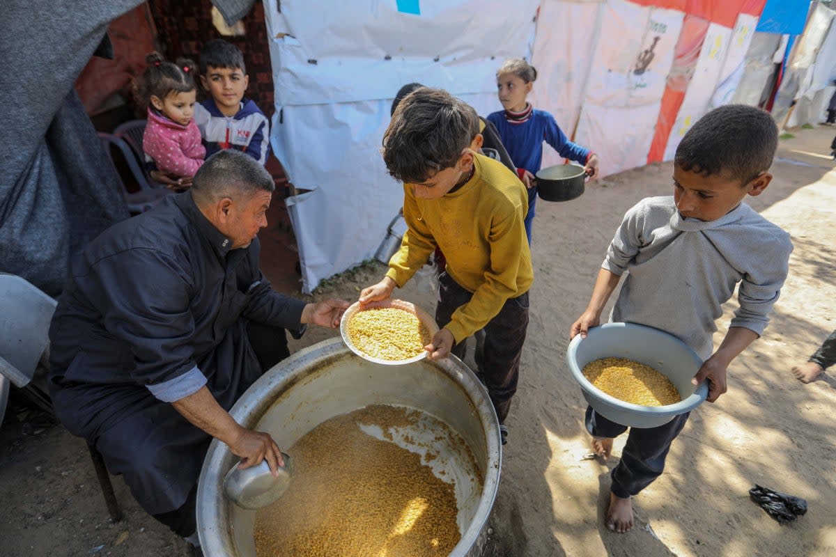 People queue for food that is cooked in large pots and distributed for free in Rafah, southern Gaza (Getty)