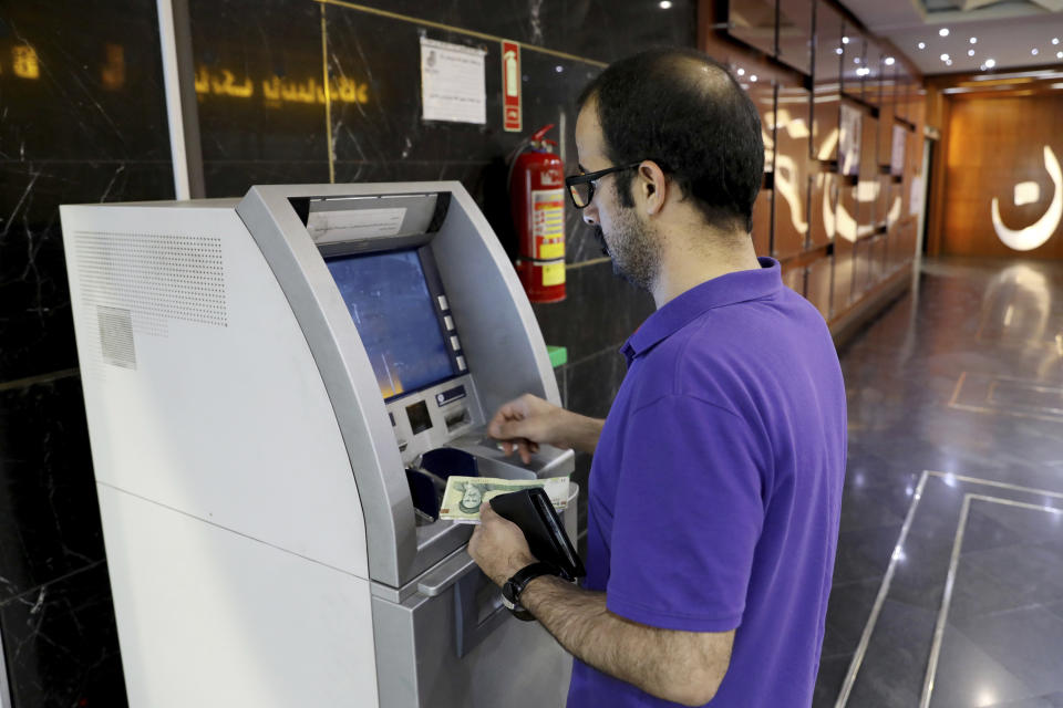 A man uses an ATM in Tehran, Iran, Wednesday, Aug. 21, 2019. Iran's president sent a bill to parliament Wednesday that would cut four zeroes from the value of the Islamic Republic's sanctions-battered currency, the rial, as tensions remain high between Tehran and Washington. (AP Photo/Ebrahim Noroozi)