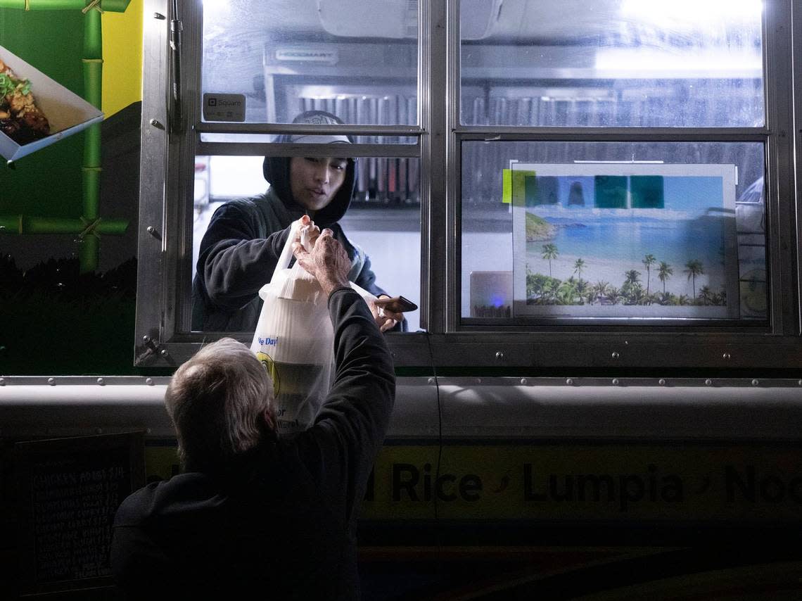 Bridgette Orosco serves a patron from a food truck at Red’s Corner during the Moore County power outage on Monday, Dec. 5, 2022, in Southern Pines, N.C.