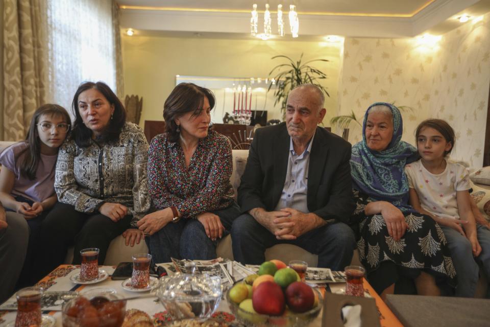 Bahar Aliguleyeva, third left, sits between her relatives; niece Maryam Mehraliyeva, left, sister Kamala Aliguleyeva, second left, father Mubariz Aliguleyeva, third right, mother Sayyara Aliguleyeva, second right, niece Maryam Mehraliyeva, in her apartment in Baku, Azerbaijan, Saturday, Oct. 7, 2023. "I often saw in my dreams how my neighbors and I, as before, were walking in the forest and picking flowers," Bahar Aliguleyeva said of her memories of childhood in the Karabakh capital city of Khanhendi, called Stepanakert by Armenians, which she left in 1988 at age 16. (AP Photo/Aziz Karimov)