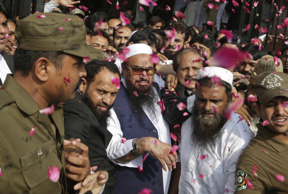 FILE - In this Oct. 19, 2017 file photo, supporters of Hafiz Saeed, center, head of the Pakistani religious party, Jamaat-ud-Dawa, is showered with rose petals by his supporters as he arrives to a court in Lahore, Pakistan. Saeed is India's most wanted man who also has a $10 million U.S.-imposed bounty on his head, lives in Pakistan. Pakistan got a mixed review for its efforts to curb terrorist financing and money laundering as it tries to avoid being blacklisted by the Financial Action Task Force, a global watchdog, when it meets in Paris Wednesday, Oct. 16, 2019. (AP Photo/K.M. Chaudary, File)