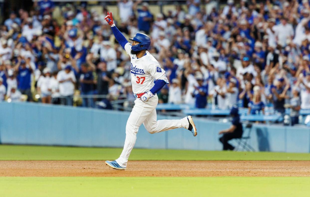 Teoscar Hernández raises a hand as he runs.